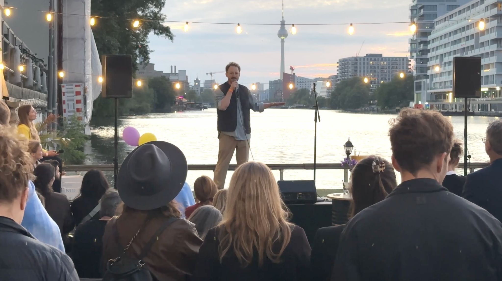 Daniel Rieber bei einem Stand-Up-Auftritt auf einer Bühne am Wasser